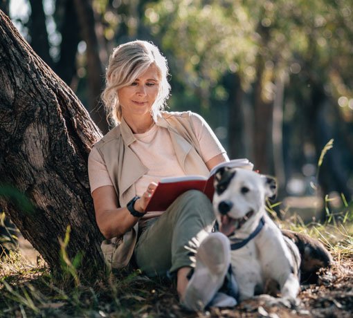 Woman reading outdoors with dog
